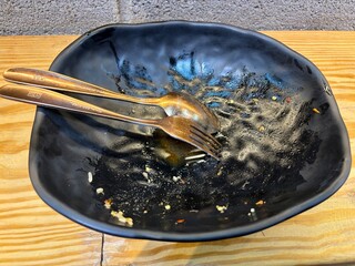 Empty bowl of Pad Kra Pao Beef, Stir-fried Beef with Holy Basil, dark-colored bowl, Local restaurant in Bangkok, Thailand - obrazy, fototapety, plakaty