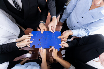 Top view multiethnic business people holding jigsaw pieces and merge them together as effective...