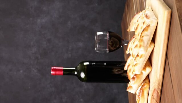 Chilean wine glasses and bottle and empanadas variety. Chile Food background. Fresh ingredients on wood. Selective Focus, vertical video