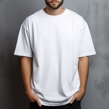 Man in white oversize t-shirt on gray wall for clothing mockup