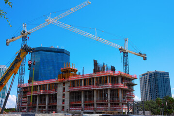 City first-stage building construction showing blocks, concrete and steel makings of the structure with large cranes on a sunny blue sky morning. - 750310101