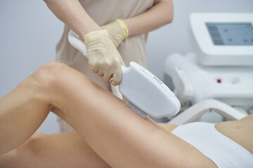 A professional beauty spa offers laser hair removal. A woman undergoes the painless treatment,...