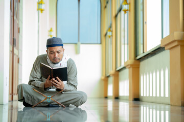 Ramadan, Quran, Islam,  An Asian Muslim man is sitting and reading the Quran. The peace in the mosque makes it an energetic atmosphere of faith, with copy space.
