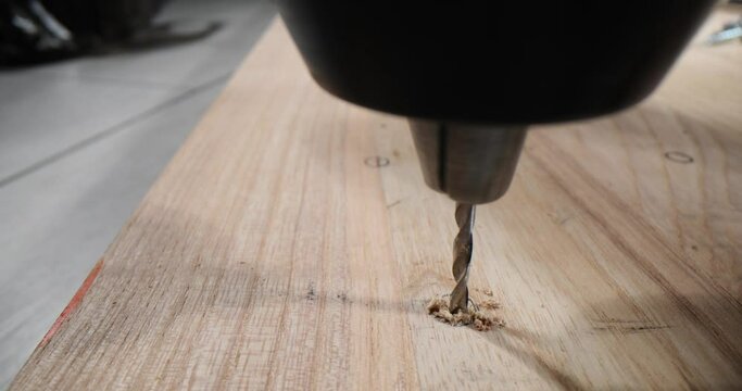Man uses cordless drill or impact driver in wood at construction site