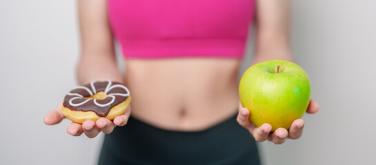 woman hand hold green Apple and donut, female fitness choose between fruit is Healthy and sweet is...