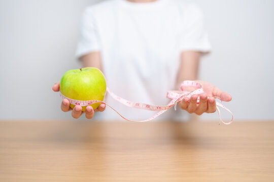 woman hand hold green Apple with tape measure, happy female choose fruit is Healthy food. Dieting control, Weight loss, Obesity, eating lifestyle and nutrition concepts