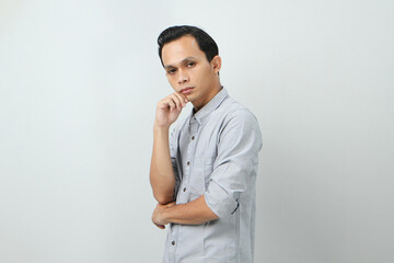 Pensive young Asian Indonesian man with a serious face thinking about a question, thoughtful about confusing idea on isolated background