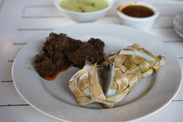 Traditional food in Malaysia known as Ketupat. It is rice cooked in woven coconut leaves, and served with rendang, chicken curry, lodeh and spicy peanut sauce.