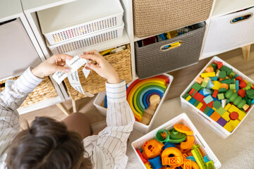 Woman mother applying paper sticker with name title on basket container clean out of childish toys