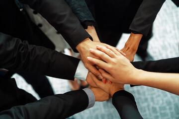 Many happy business people stacking hands together with joy and success. Company employee celebrate...