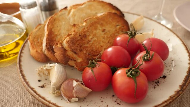 Preparation of appetizing Catalan tapas Pan con tomate - grilled bread topped with mixture of grated tomatoes and garlic. Ingredients ready for cooking served on table