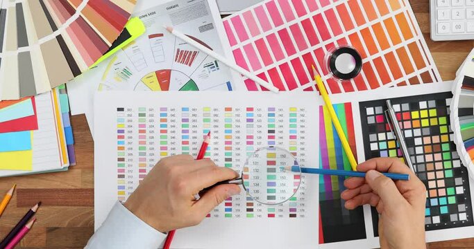 Male designer uses magnifying glass in search of perfect color for project