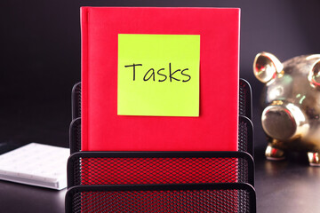 Business concept. TASKS - word on a yellow sticker glued to a red notebook