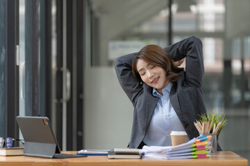 Asian businesswoman working in an office stretches to relax from work during breaks.