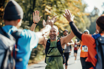 Happy marathon runners giving high-five to each other during the race in nature