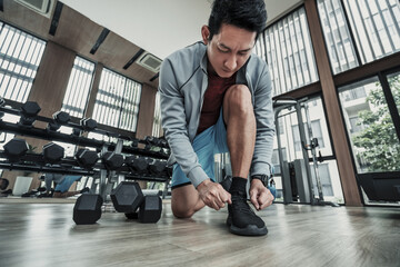man's hands tying shoe laces in the gym.  Fitness, workout and traning at concept.