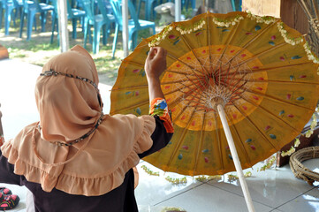 a woman is arranging jasmine flowers to decorate paper umbrellas