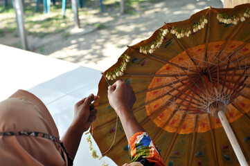 a woman is arranging jasmine flowers to decorate paper umbrellas