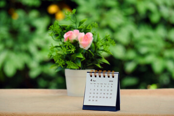 Calendar desk with plants and flowers in pots on blurred natural background.