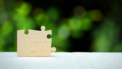 Puzzle pieces on natural bokeh background. Concept of solution, mission, success, goal, cooperation, partnership and strategy concept