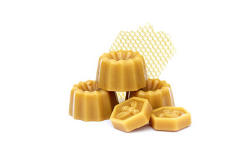 Shaped pieces of natural bee wax piled up with honey comb fragment on a linen background