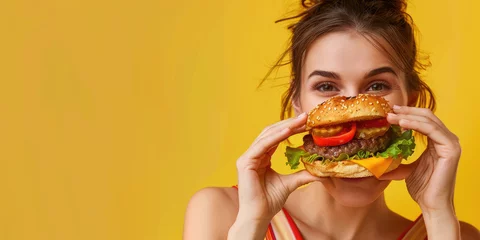 Rucksack portrait of a young woman eating delicious hamburger on color background, copy space © Kien
