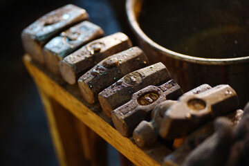 Close-up of an old forge hammer in a wooden rack, blacksmith tools 