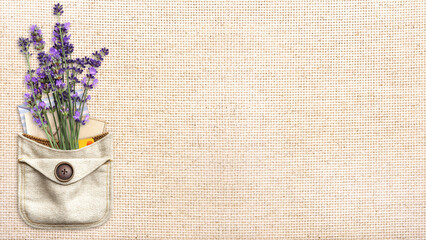 Purple lavender flower and retro envelopes in pocket. Bunch of fresh lavandula flowers in pouch on canvas texture backdrop. Horizontal eco background with natural linen texture. Copy space for text