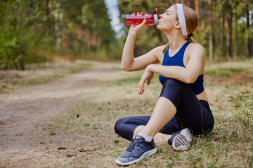Sportive woman drinking water during outdoors workout
