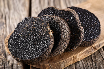 Thinly sliced black truffle mushrooms meticulously arranged on a rustic wooden cutting board, showcasing their aromatic essence and culinary finesse.
