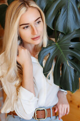 Naklejka premium Close up of beautiful girl face everywhere leaves green houseplant