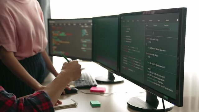 Slow motion back end software developer engineer for computer programming working together on debugging writing computing code, solving complex algorithms display on monitor in office. Burgeoning
