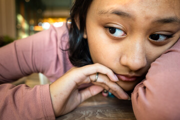 Asian Teenage Girl in a Bad Mood Lying Her Body and Putting Her Arms on Table