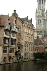 Bruges in Belgium. Historic houses in the city center with a church in the background.