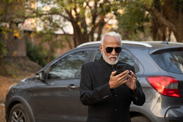 Lifestyle shot of senior Indian man wearing a suit working on a phone Digital India and digitally...