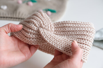 Female hands hold a knitted product - a head bandage for a girl