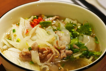 A close-up of a Vietnamese pho soup with chopsticks.