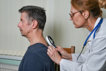 Doctor examining a patient at an appointment. A female GP wearing a white coat checks her patient's...