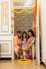 Happy indian family of three doing grah pravesh ritual or entering new house for the first time....