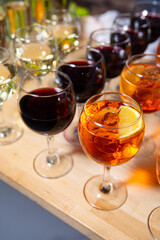 Assorted Wine Glasses on Wooden Surface. Variety of wine glasses filled with red, white, and aperitif wine, displayed on a wooden table.