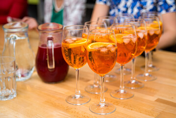 Aperol Spritz Cocktails in Glasses on Table. Refreshing Aperol Spritz cocktails served in wine glasses, garnished with orange slices, perfect for a social gathering or party.
