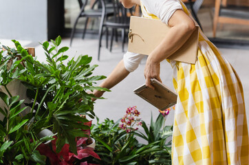 Cropped shot of unrecognizable woman holding potted flower plant in garden shop.