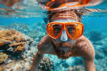 Poster Caucasian man in a mask swims on a coral reef © sofiko14