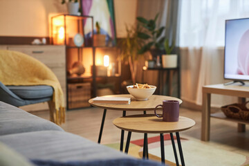 Close up of wooden coffee table with drink and snacks at TV area in cozy living room copy space