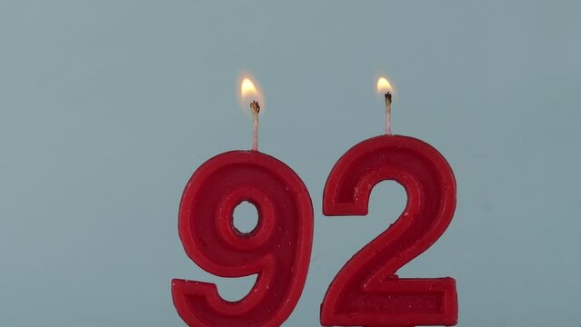 close up on a red number ninety two birthday candle on a white background.
