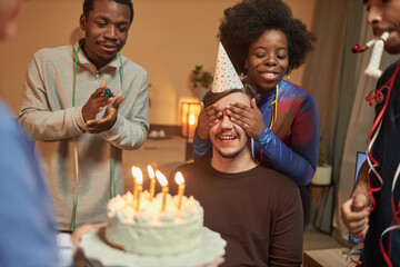 Multiethnic group of friends surprising young man with disability at Birthday party and celebrating...