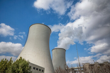 Industrial Cooling Towers Emitting Steam Against Cloudy Sky