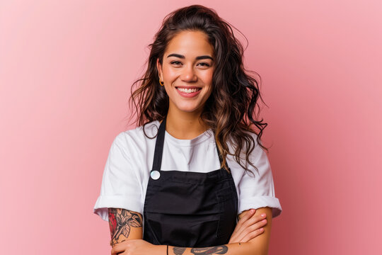A woman with long hair and a black apron is smiling and posing for a picture