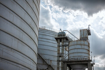 Industrial Metal Staircase on Storage Tank Against Cloudy Sky