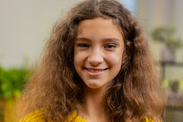 Close-up portrait of happy smiling cheerful Caucasian school girl 14-15 years old. Young adult lovely attractive child kid student looking at camera at home play living room apartment. Childhood